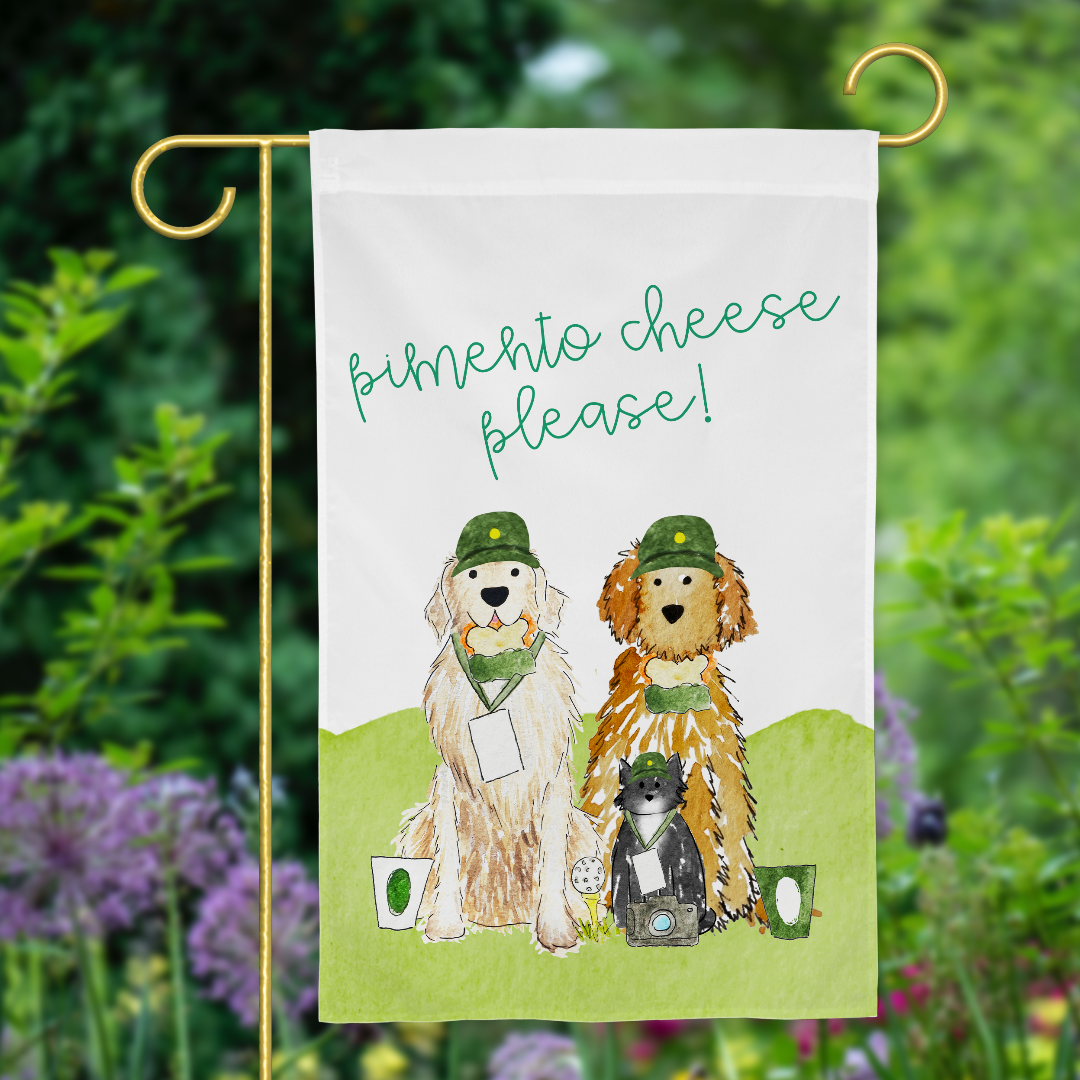 A golf garden flag featuring hand-painted watercolor art of three pets, each with a green cap, a pimento cheese sandwich, a golf tournament cup, and golf tournament ticket. At the top it reads, "Pimento Cheese, Please!' displayed in a garden setting.