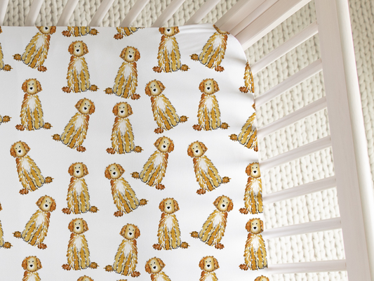 Top view of crib with fitted crib sheet featuring Apricot and Cream Doodles in a watercolor pattern. doodle crib sheet, apricot doodle baby bedding, cream doodle crib sheet, goldendoodle crib sheet, labradoodle crib bedding, dog nursery crib sheet, doodle baby gift, goldendoodle baby nursery, baby sheet for dog lovers, watercolor doodle crib sheet, baby shower gift for dog mom, jersey knit crib sheet, dog lover baby bedding, apricot goldendoodle crib sheet, cream labradoodle nursery decor