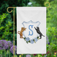 Custom dog garden flag featuring a golden retriever and labrador with family monogram, displayed in garden setting.